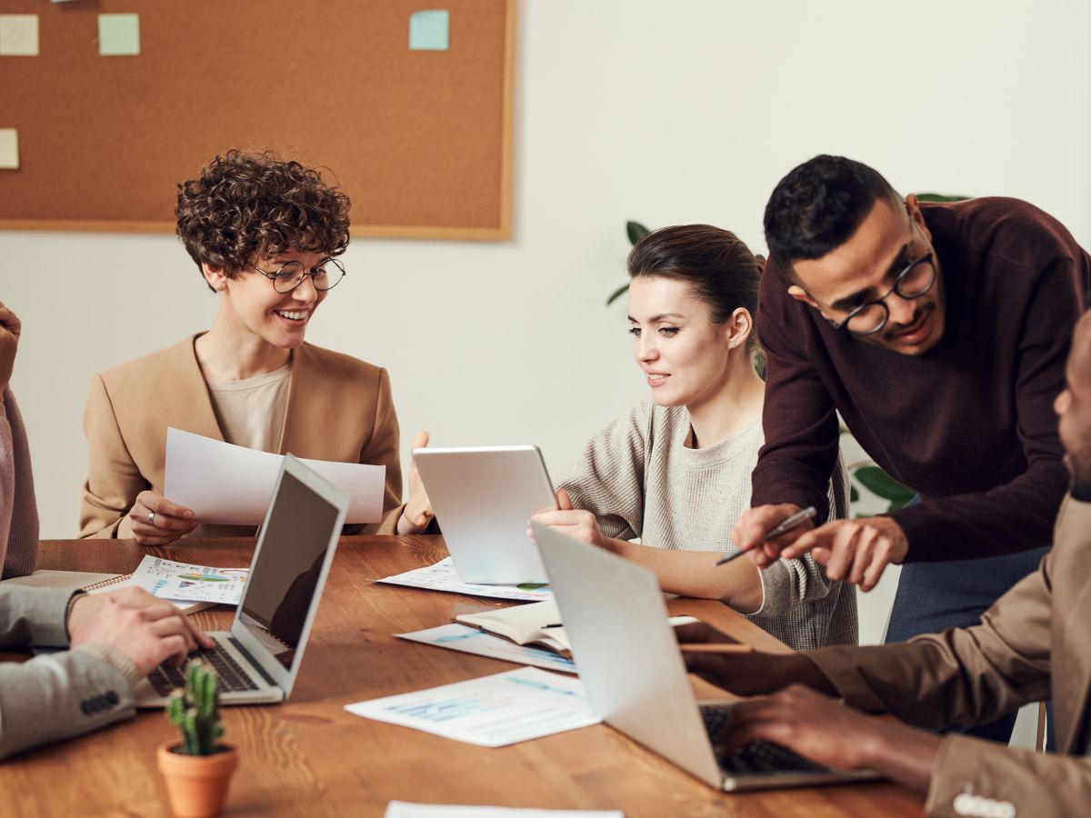 Diverse professionals collaborating around a conference table with laptops and reports